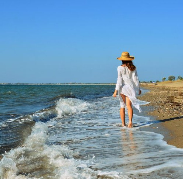 Vrouw geniet van een zomerse dag buiten met zonbescherming aan het strand